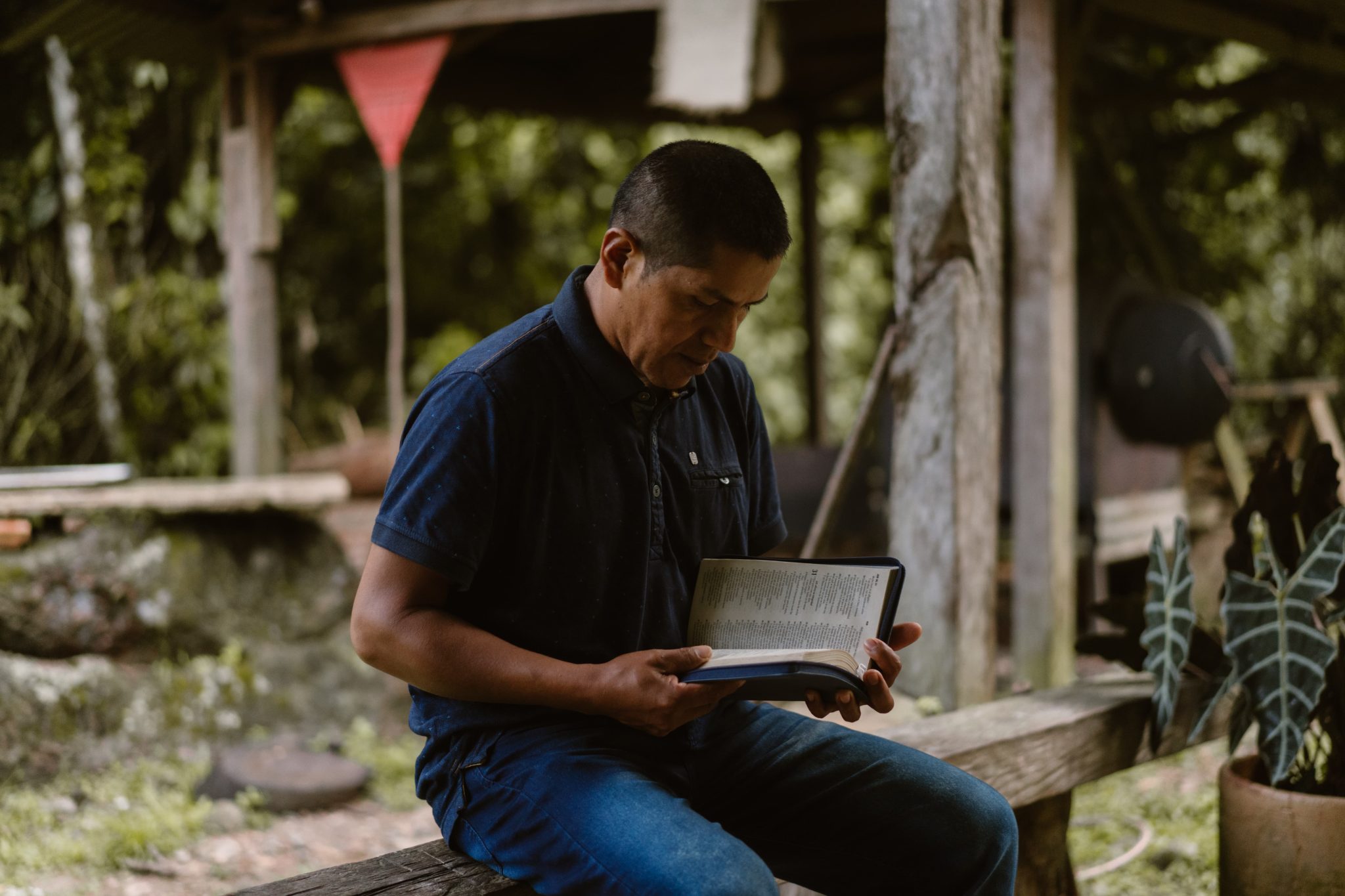 Kolumbialainen Fransisco lukee Raamattuaan ja istuu kaiteella.