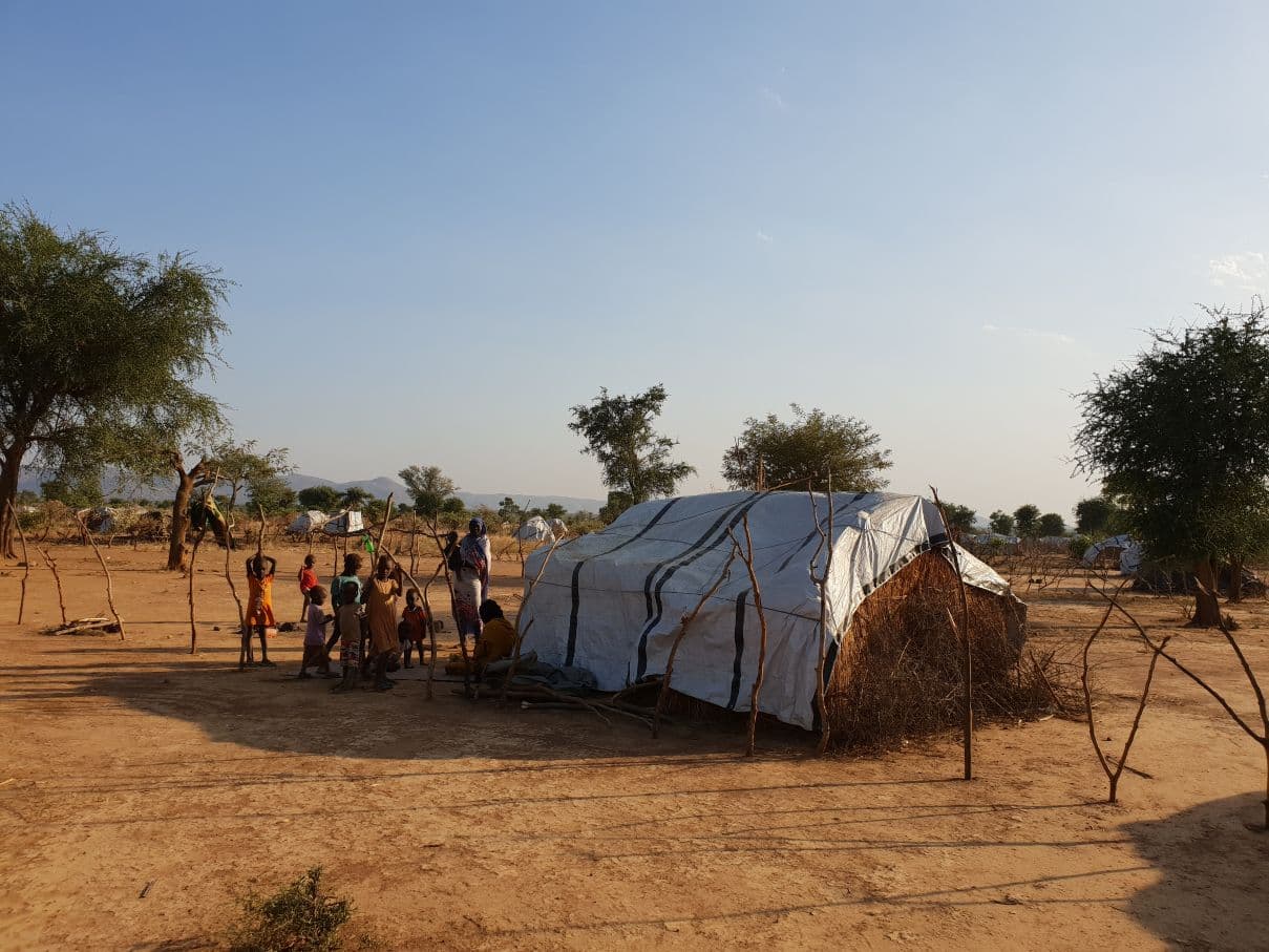 Valokuva teltasta pakolaisleirissä sekä sudanilaisia lapsia leikkimässä sen ympärillä.