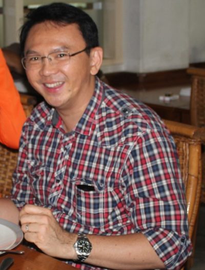 Indonesialainen mies hymyilee silmälaseissa ja ruutupaidassa.