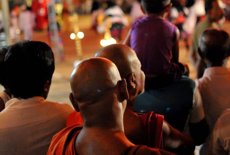 Kaksi buddhalaismunkkia kävelee väkijoukossa kasvot kamerasta poispäin