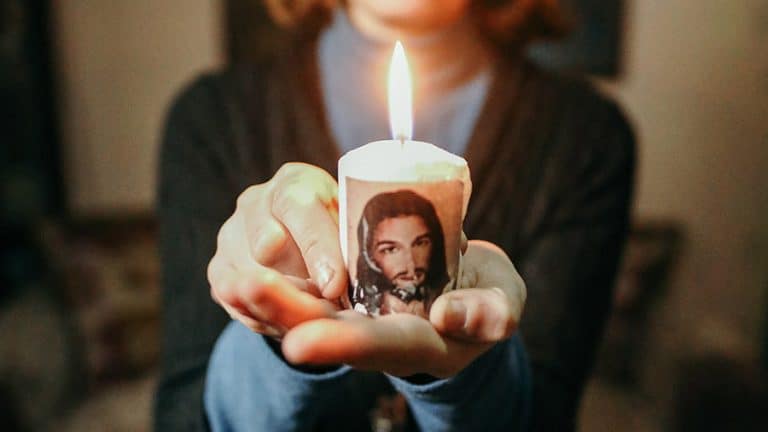 Syyrialainen nainen pitelee kadessaan kynttilaa, jonka sivussa on kuva Jeesuksesta