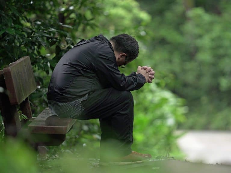 Kiinalainen Open Doorsin tyontekija rukoilee penkilla puistossa