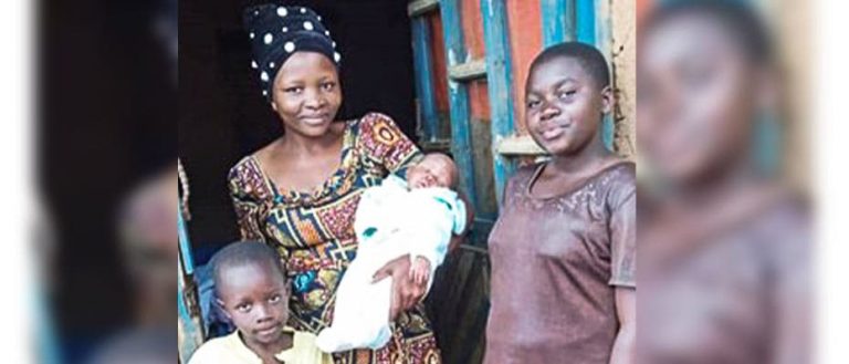 Kongolainen Esther hymyilee lastensa kanssa ovensuussa