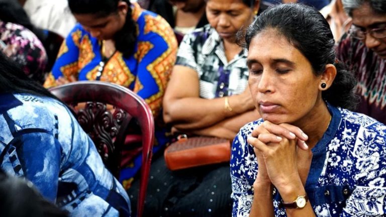 Ihmisiä kirkossa rukoilemassa.