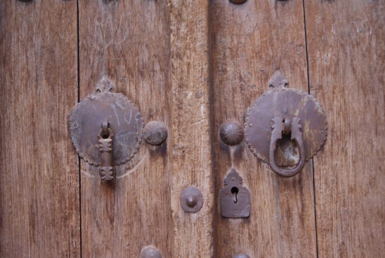 Lähikuva vanhan oven yksityiskohdista. Ovi on kulunut ja siinä on rautaisia yksityiskohtia sekä avaimenreikä.