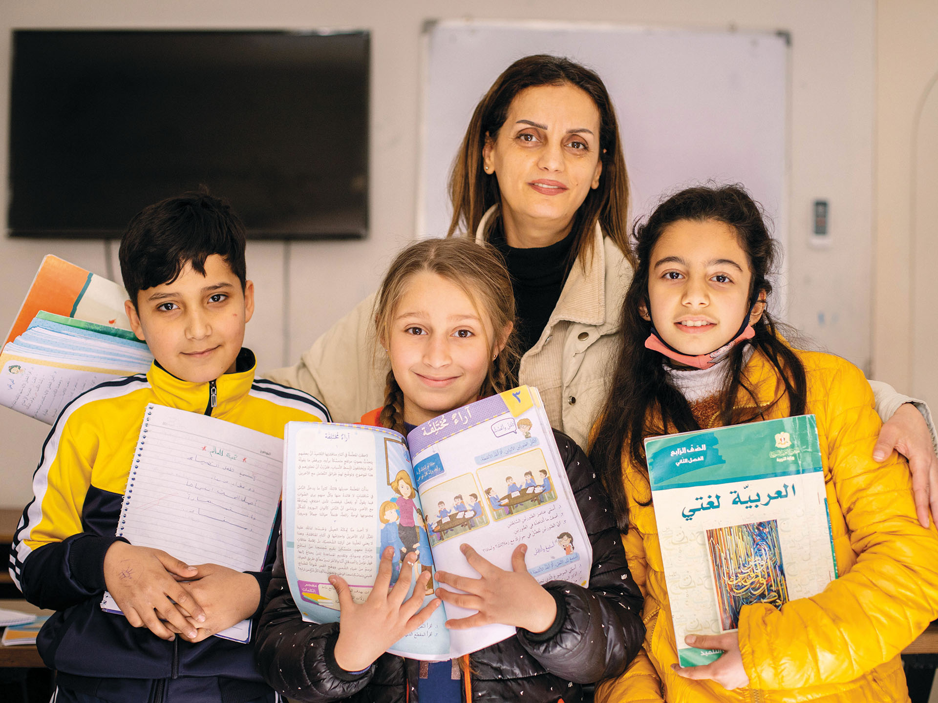 Ferial kolmen oppikirjoja pitelevän syyrialaislapsen kanssa Toivon keskuksessa