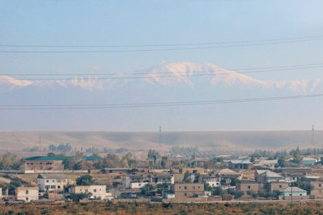 Etualalla uzbekistanilaista kaupunkia. Taustalla aroa ja lumihuippuisia vuoria.