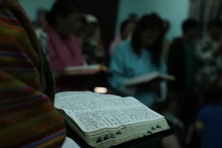 Bhutanilaiset kristityt lukevat Raamattua salaisessa kotikokouksessa hämärässä valaistuksessa