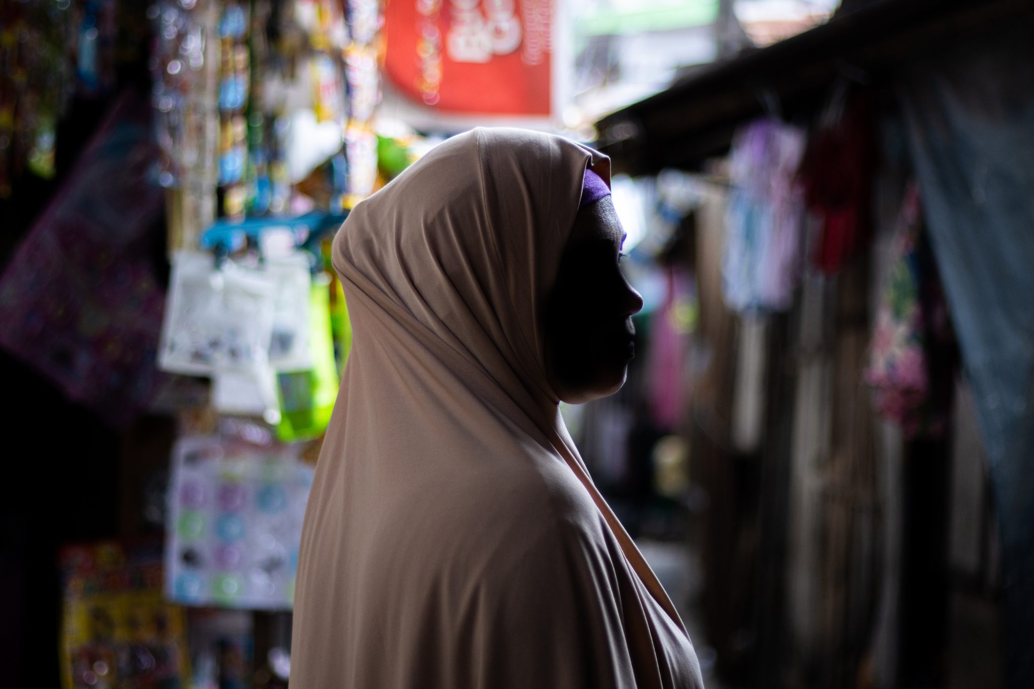 Muslimiksi pukeutunut hunnutettu nainen kasvot tummennettuina markkinakorttelissa.