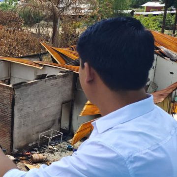 Intia mies katsoo parvekkeelta tuhottua kotiaan ja toimistoaan