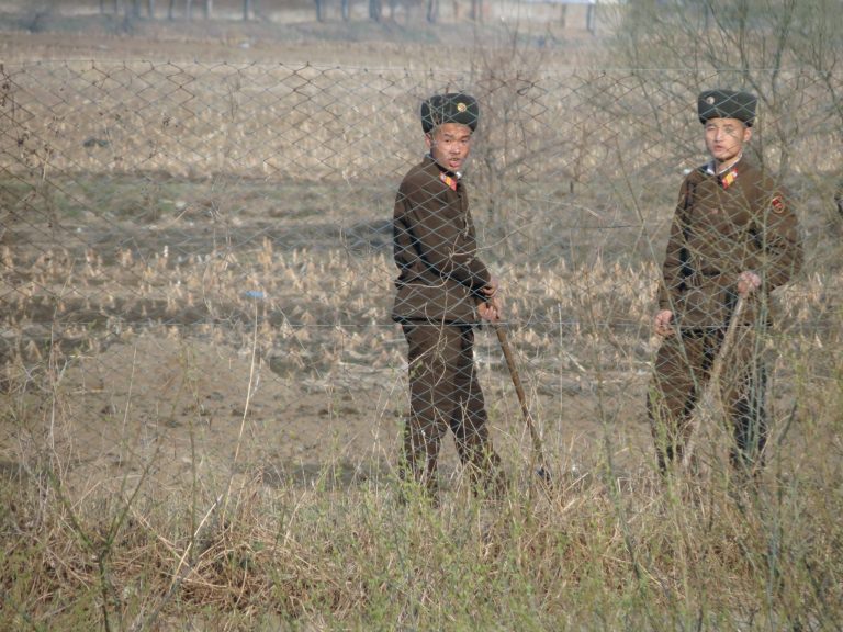 Rajavartioiden vihreänruskeisiin univormuihin pukeutuneet kaksi vartijaa seisovat pellolla.