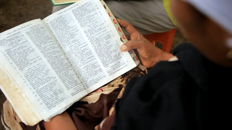 Nainen pitää käsissään raamattua.