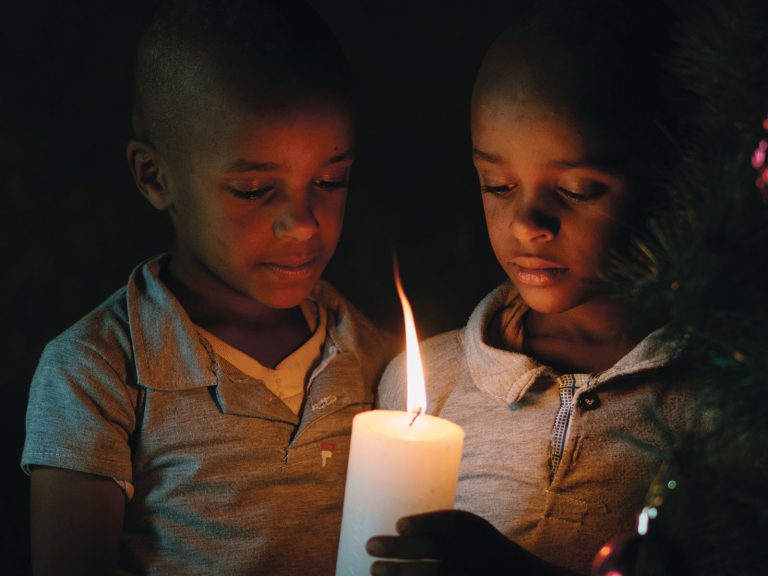 Etiopialaiset kaksoispojat pitävät palavaa kynttilää käsissään pimeässä