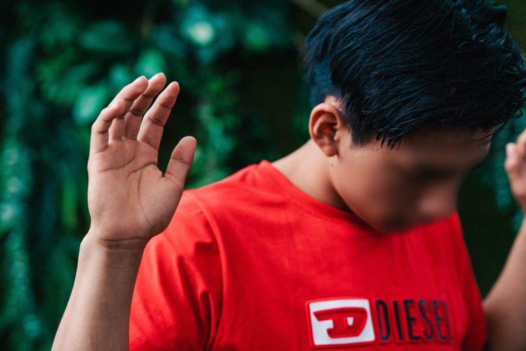 Nuori poika punaisessa t-paidassa rukouksessa kädet kohotettuna