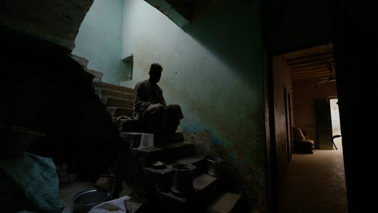 Nuori mies istuu pimeässä portaikossa