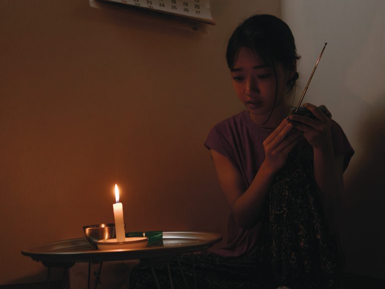Pohjoiskorealainen nainen kuuntelee radiota hämärässä huoneessa