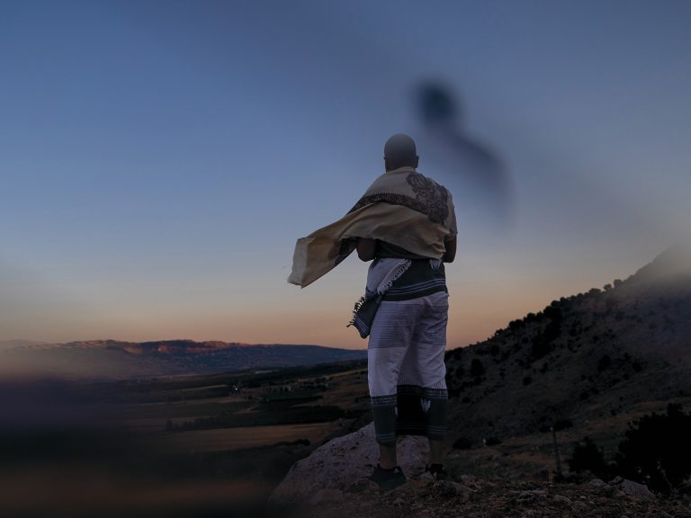 Jemeniläinen mies mäen rinteellä katsoo alla avautuvaan laaksoon