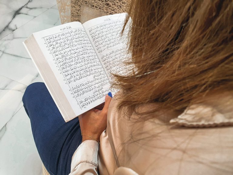 Nainen Lähi-idästä lukee Raamattua kasvot kamerasta poispäin