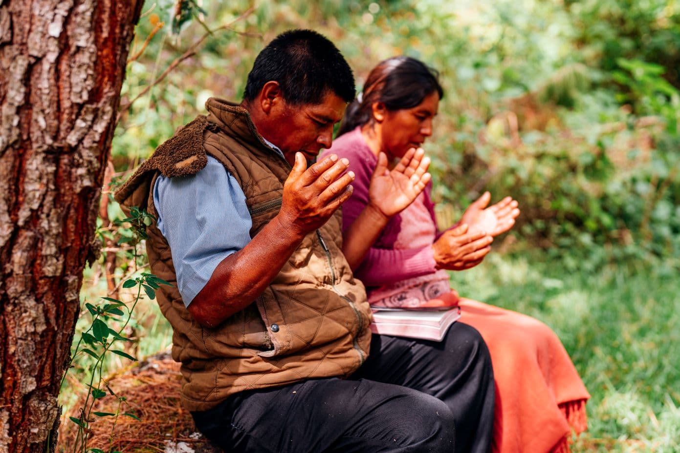 Mies ja nainen rukoilevat ulkona.