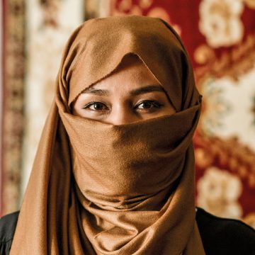 Afganistanilainen naiskristitty katsoo kameraan kasvojen alaosan peittävä kangas kasvoillaan
