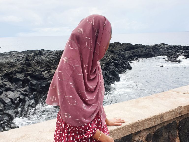 woman sitting on rocks near sea