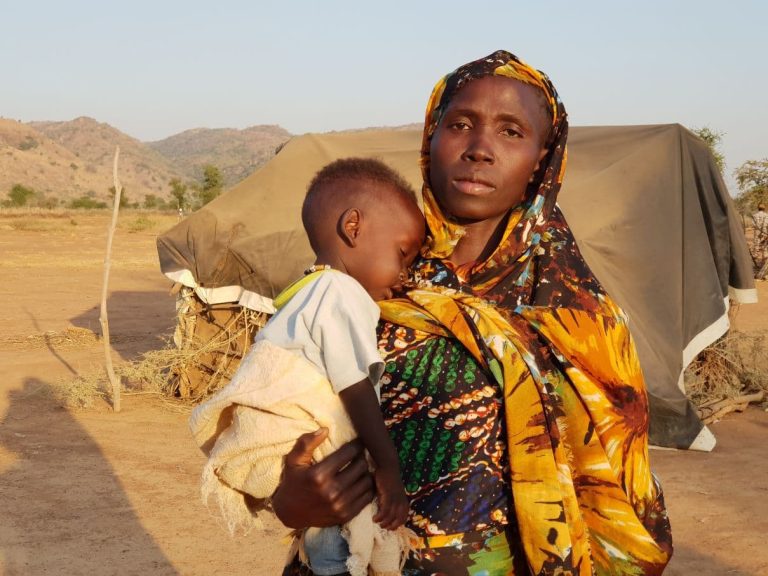 Sudanilainen nainen nukkuva lapsi sylissään.