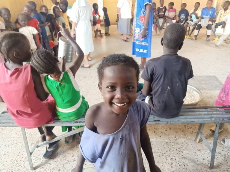 Afrikkalainen lapsi katsoo kameraa, taustalla muita afrikkalaisia lapsia.