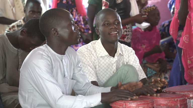 Miehet soittavat rumpuja jumalanpalveluksessa.