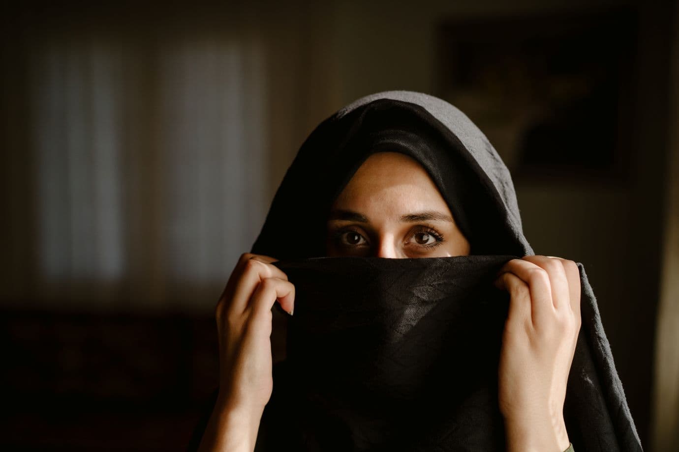 Puolet naisen kasvoista näkyvissä huivin takaa.