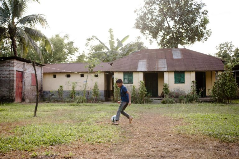 Lapsi pelaa yksin jalkapalloa.