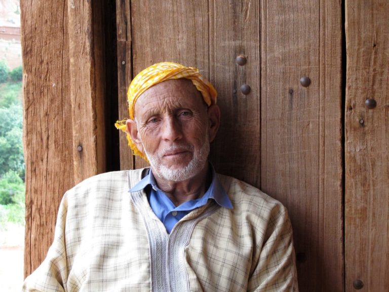 Vanha mies lautaseinän edessä.