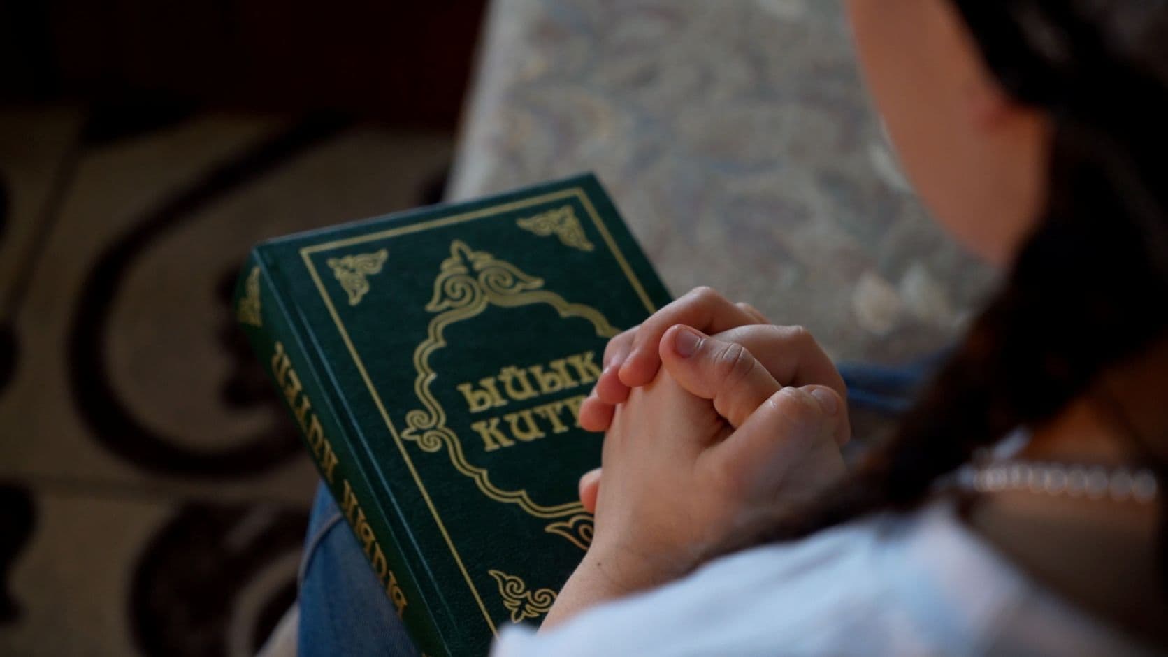 Tytön kädet ristissä Raamatun päällä.