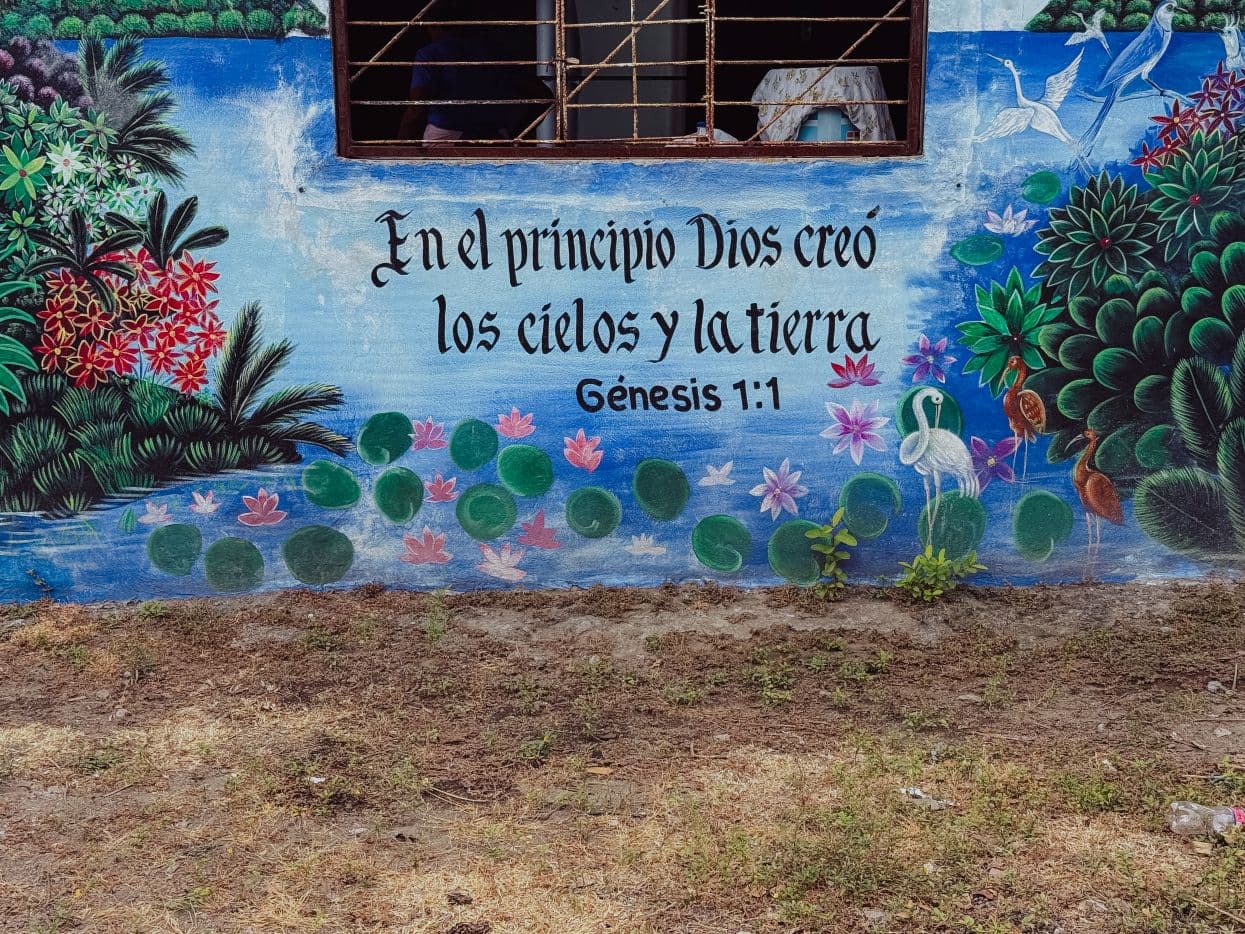 Raamatunpaikka espanjaksi talon seinässä, 1. Moos. 1:1.