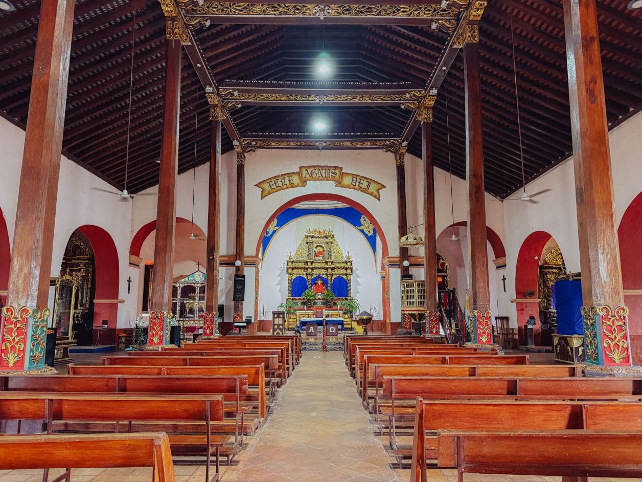 Tyhjän kirkon keskikäytävä, käytävän vierellä penkkirivit, edessä alttari.