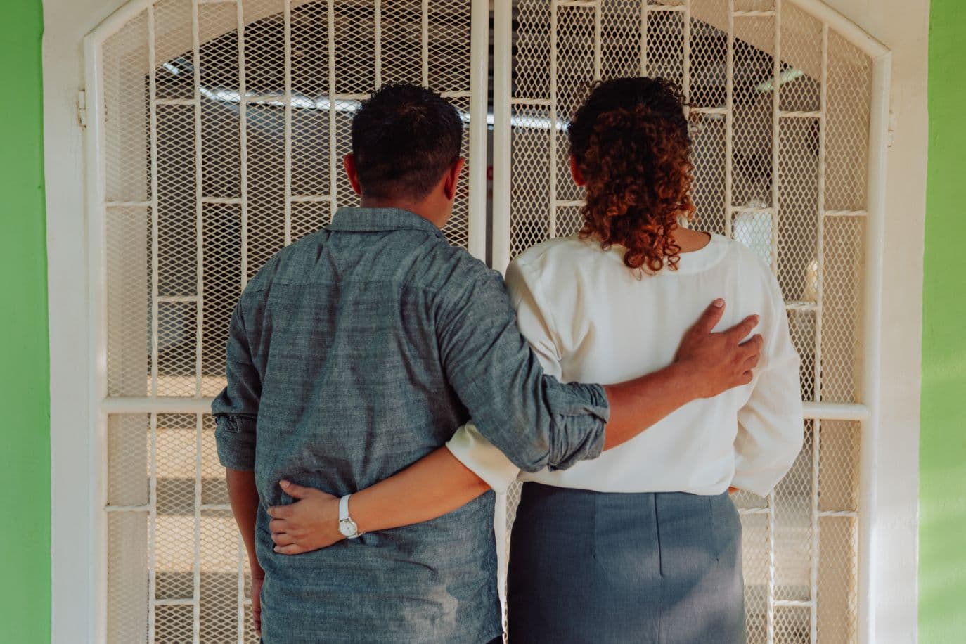 Mies ja nainen vierekkäin takaapäin kuvattuna, pitävät käsiä toistensa selällä.