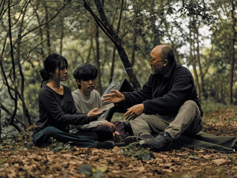 Nuoria kuuntelemassa evankelistaa metsässä