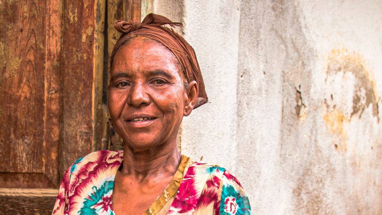 Afrikkalainen nainen päällään värikäs vaate ja huivi.