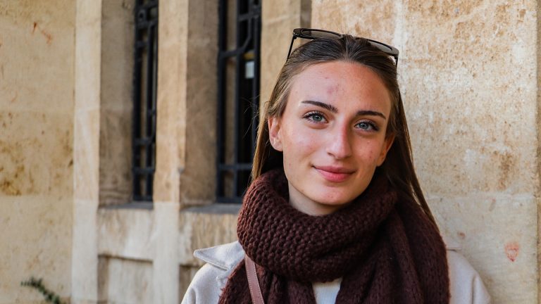 Nuori nainen kiviseinän edessä.