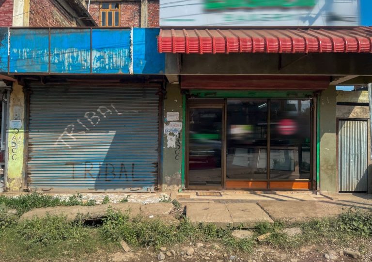 Rakennuksen seinää kadun vieressä. Seinässä autotallin kiinni oleva ovi sekä liikehuoneiston ikkunoita.