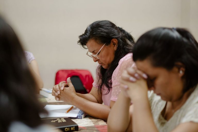 Naisia rukoilemassa pöydän ääressä.