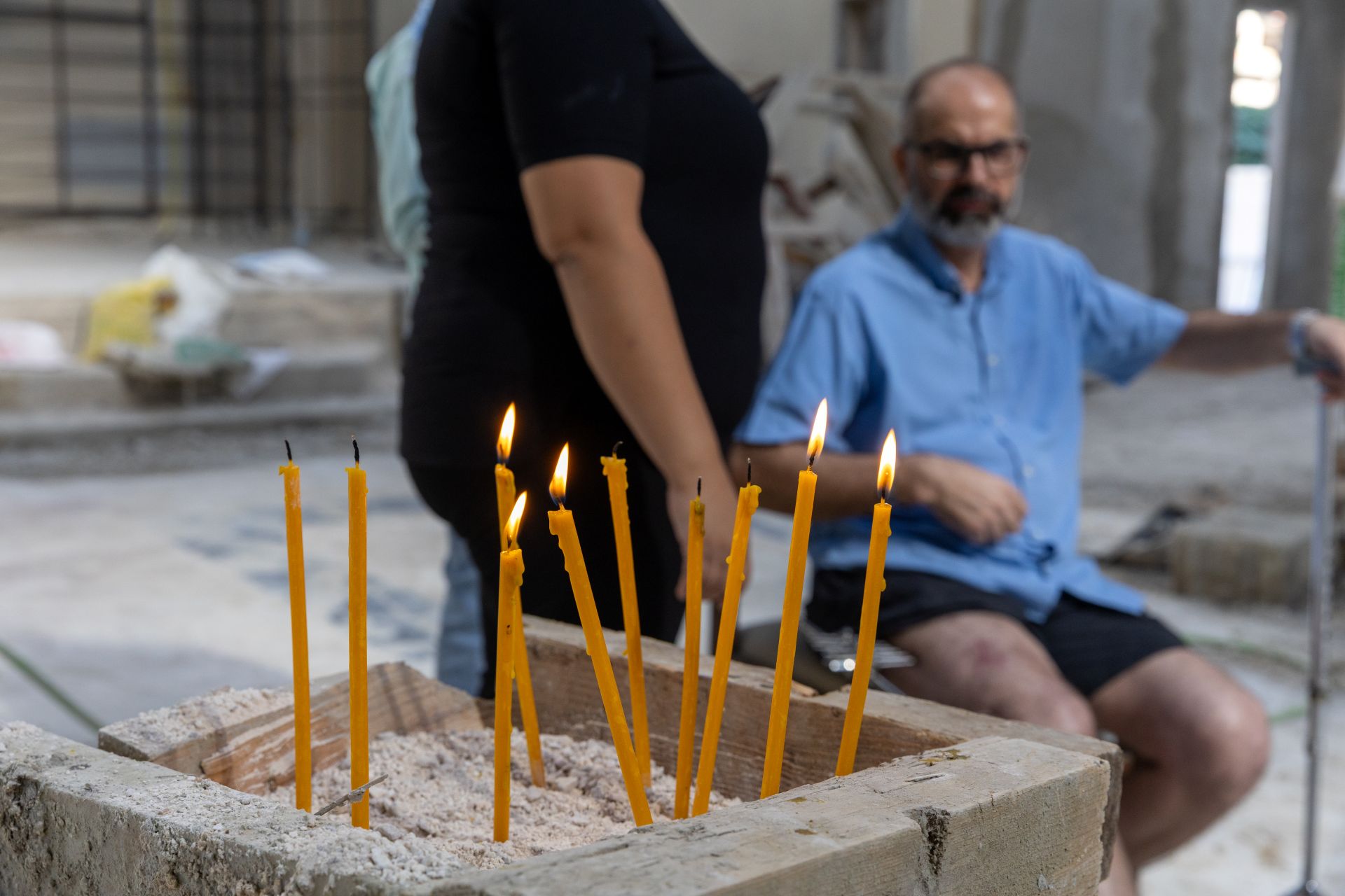 Kynttilöitä kirkossa, joita mies katselee.