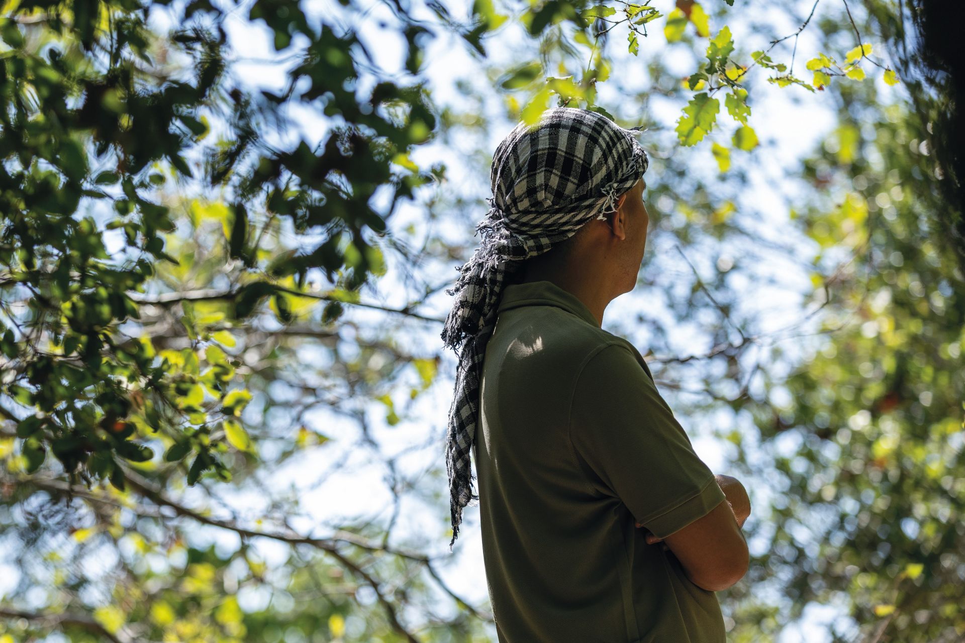 Huivipäinen mies puun varjossa.